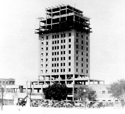 a building under construction with cars and trees