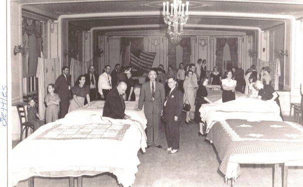 a group of people standing in a room with beds