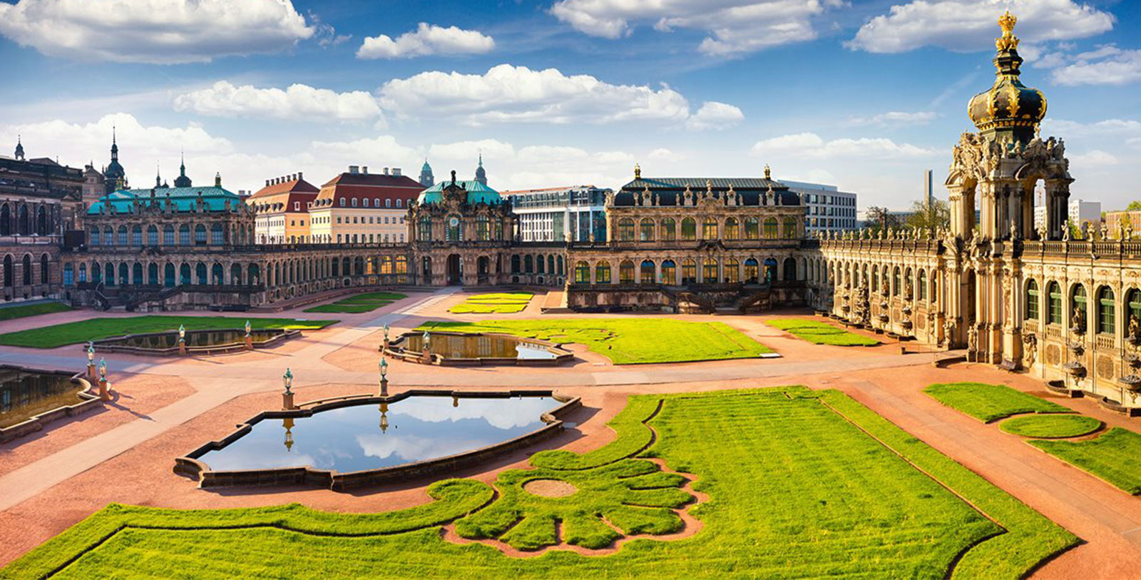 a large courtyard with a fountain and a building with a lawn and buildings