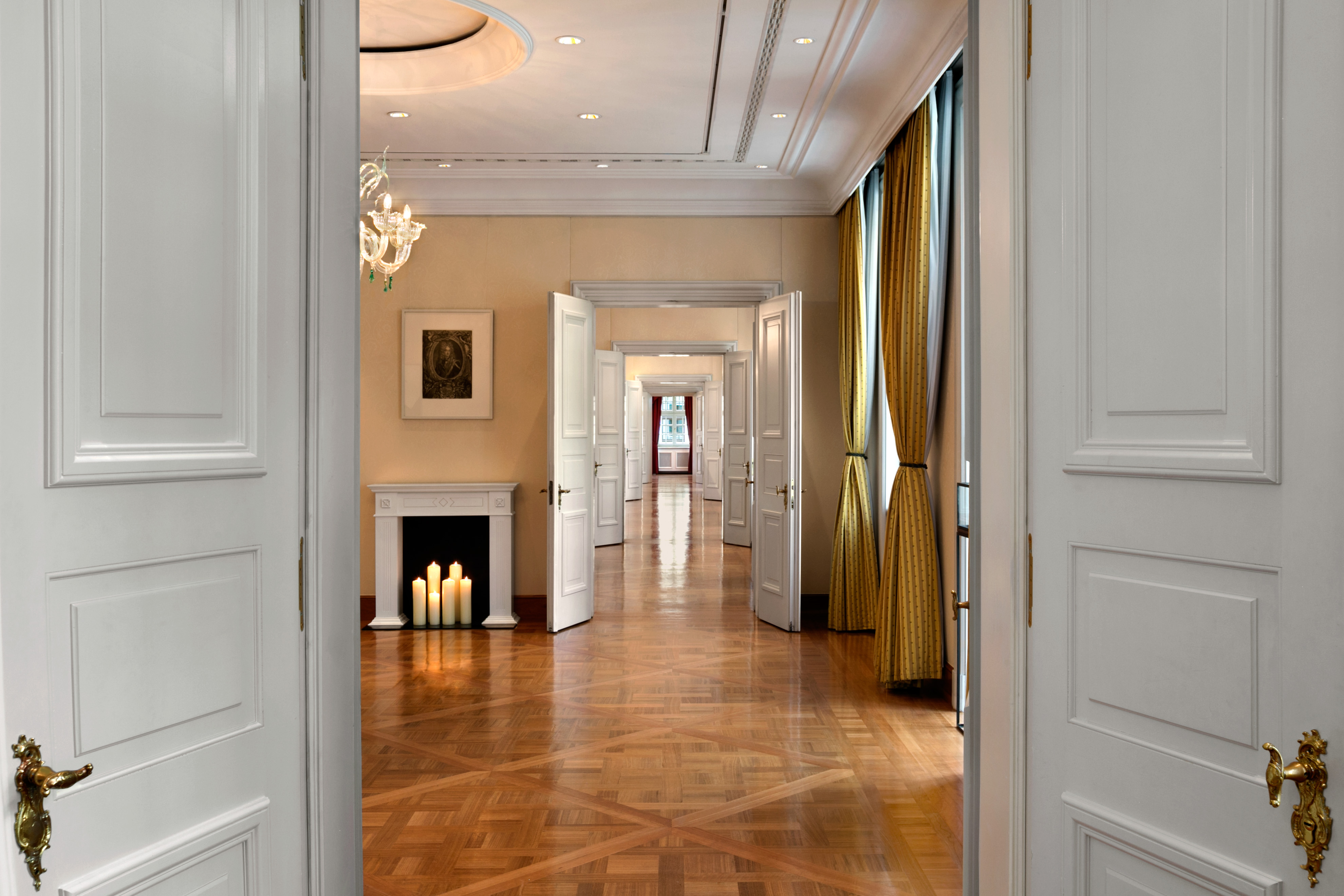 a hallway with white doors and a chandelier
