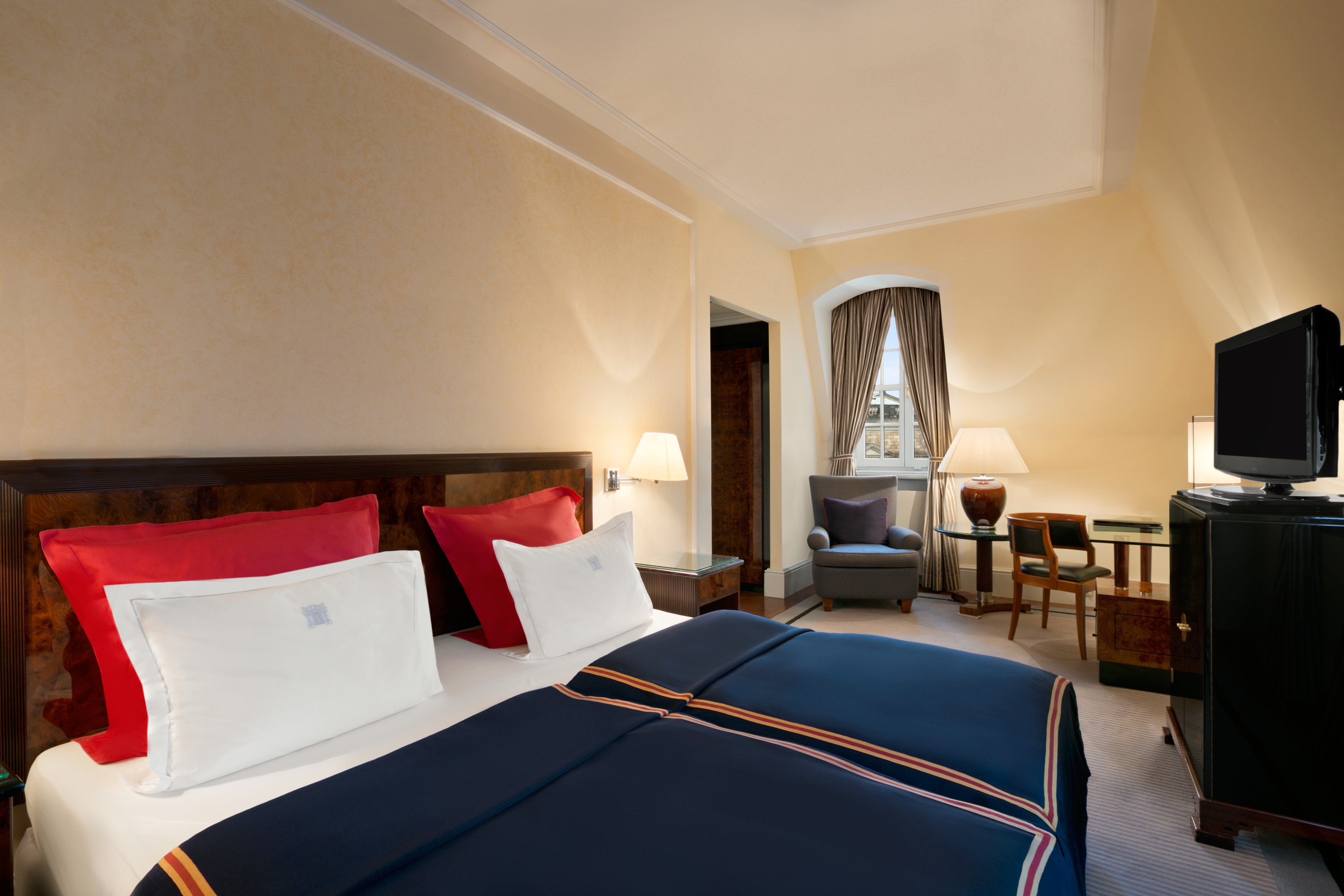 a bed with a blue blanket and red pillows in a room