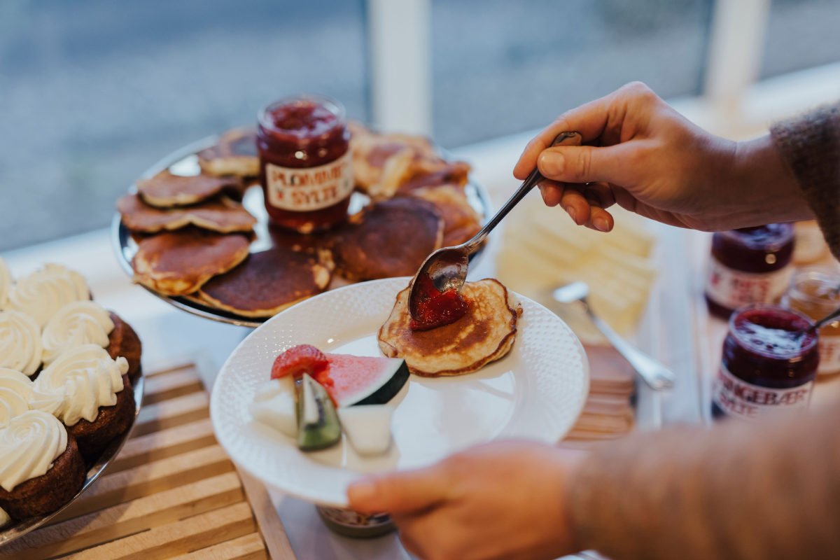 a person holding a spoon over a plate of pancakes