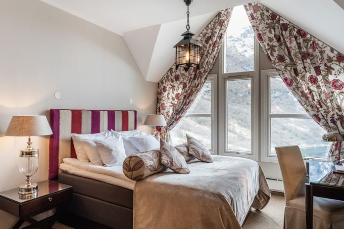 a bed with a striped headboard and a lamp in a room with a mountain view