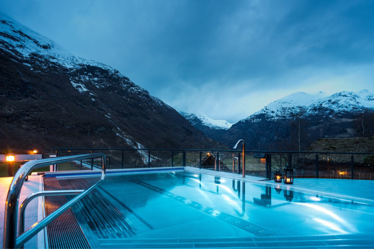 a pool with a railing overlooking a snowy mountain range