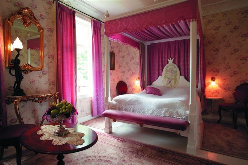 a bedroom with a canopy bed and pink curtains