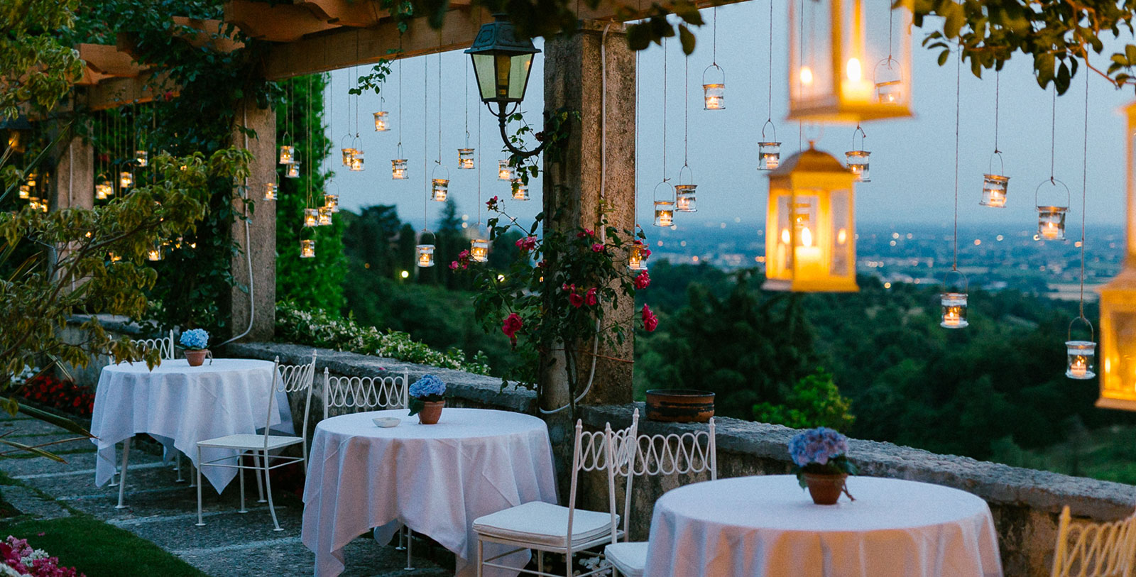 a table and chairs with lanterns from a pillar