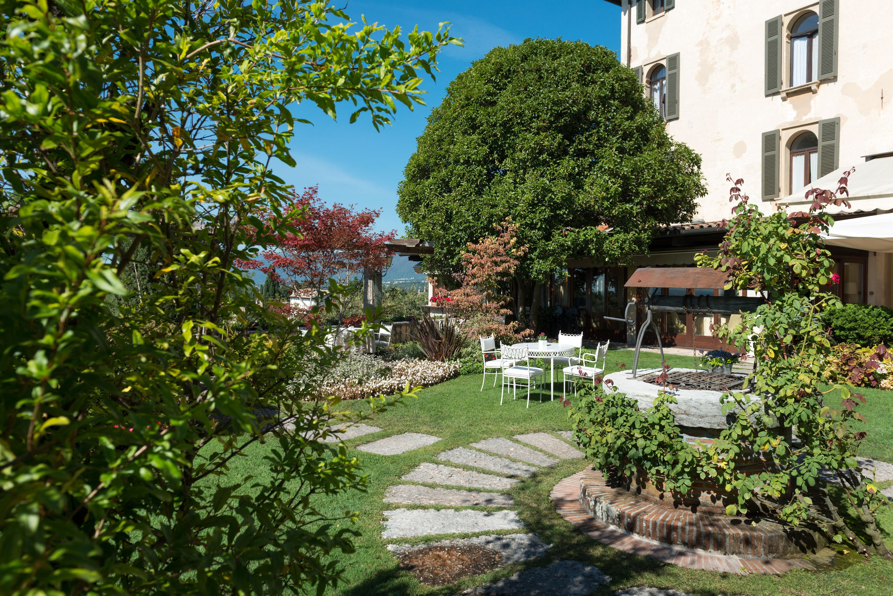 a stone path in a yard with a fountain and chairs