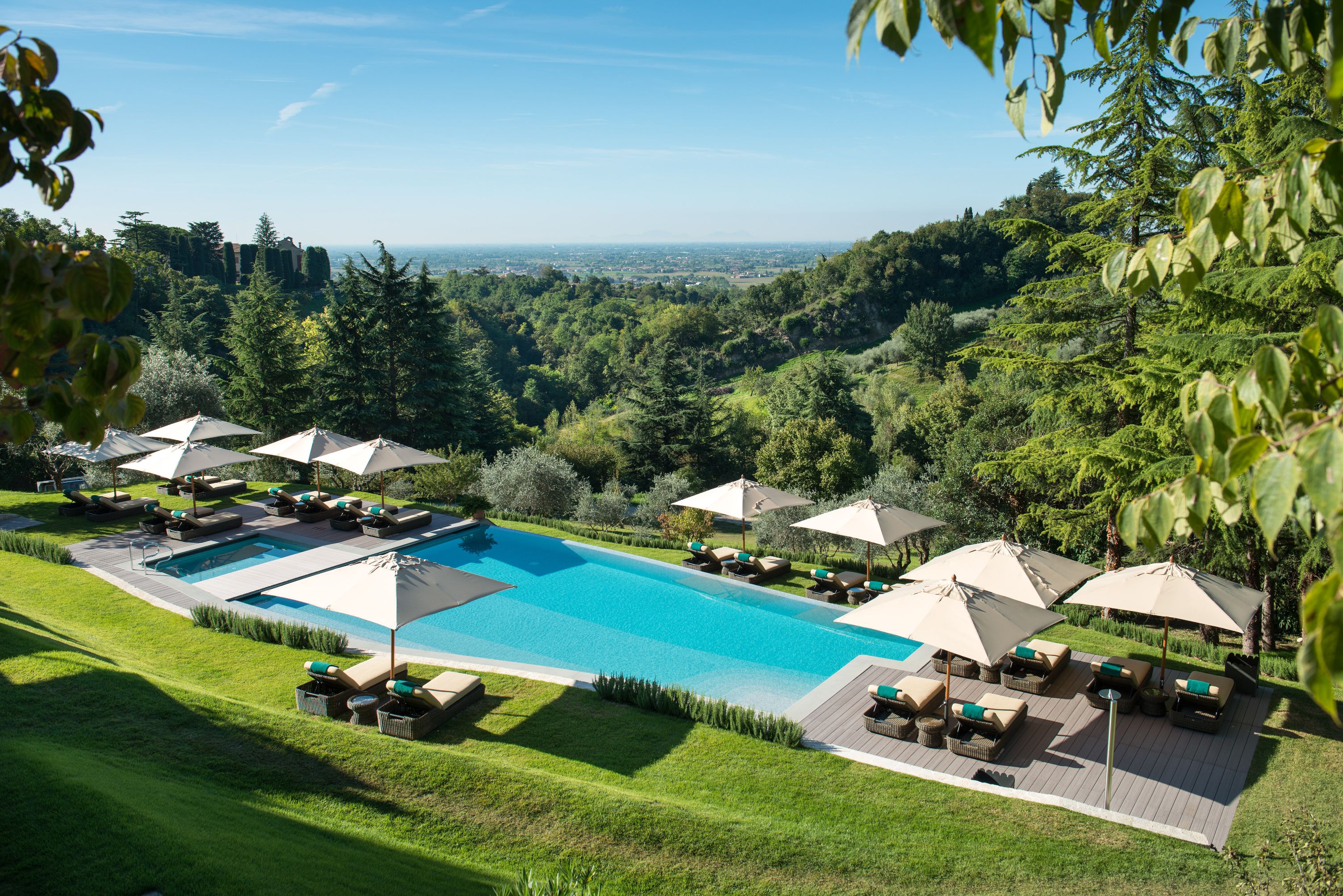a pool with umbrellas and chairs in a grassy area