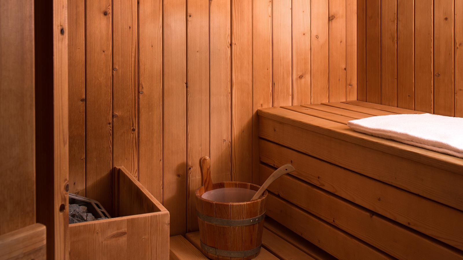 a wooden sauna with a bucket and a towel