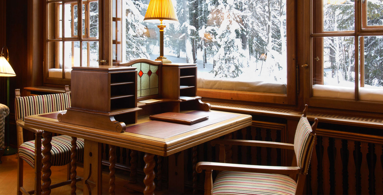 a desk with a lamp and a window in the background