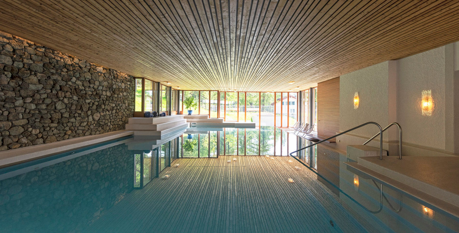 a indoor pool with a wood ceiling and a stone wall
