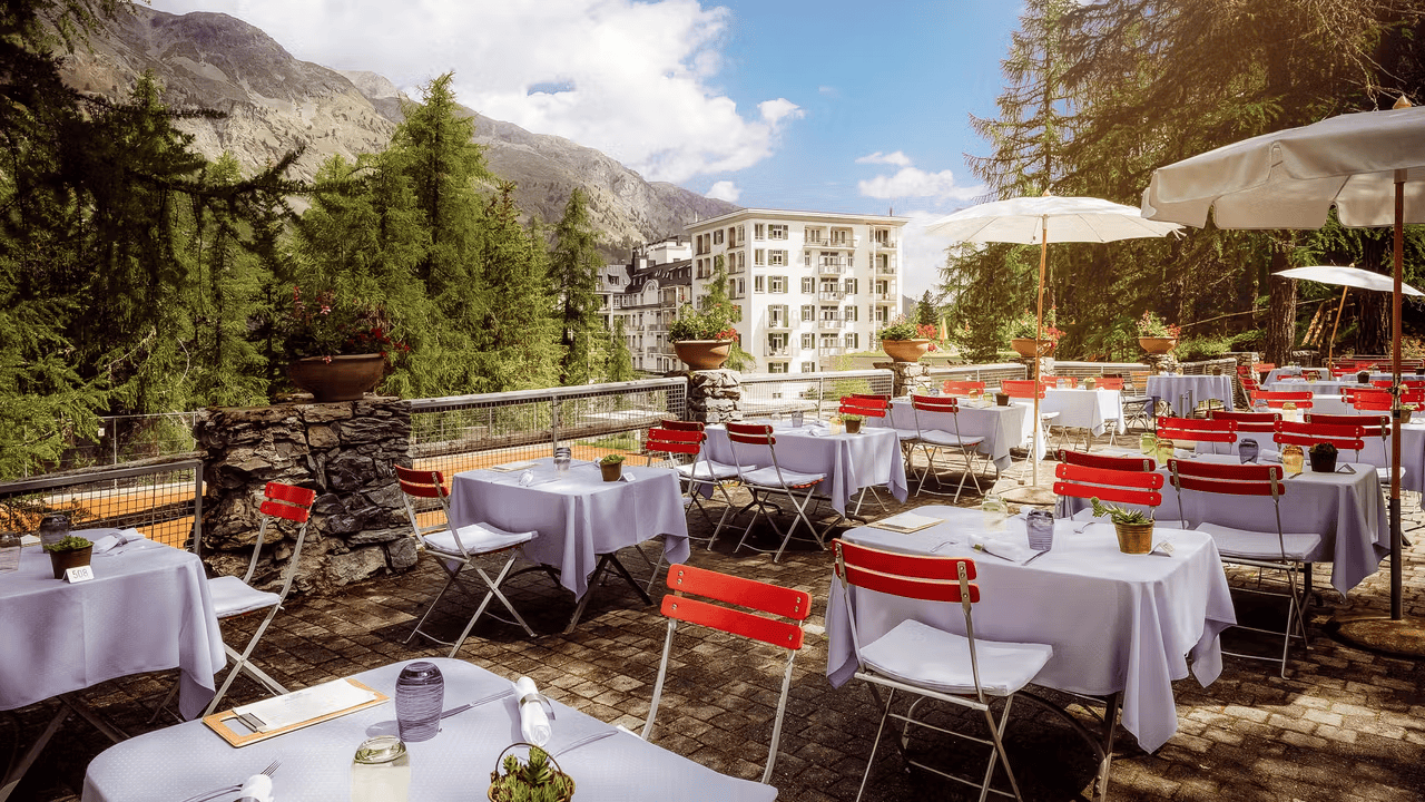 a table and chairs on a patio with a mountain in the background