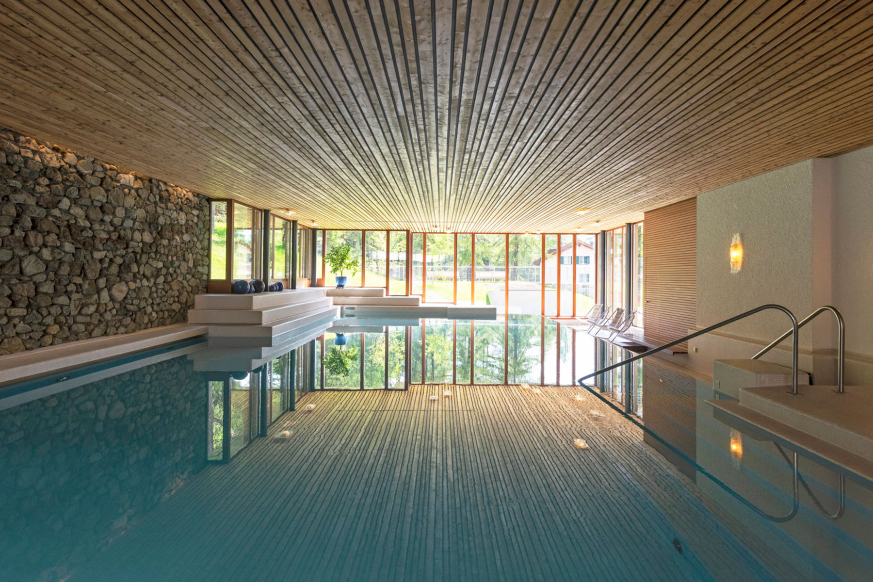 a indoor pool with a large stone wall and a large window
