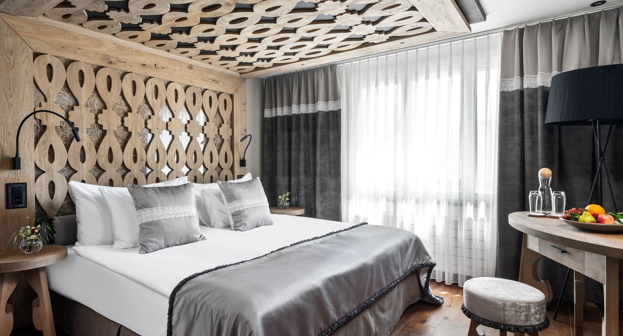 a bed with grey sheets and pillows in a room with a wood ceiling