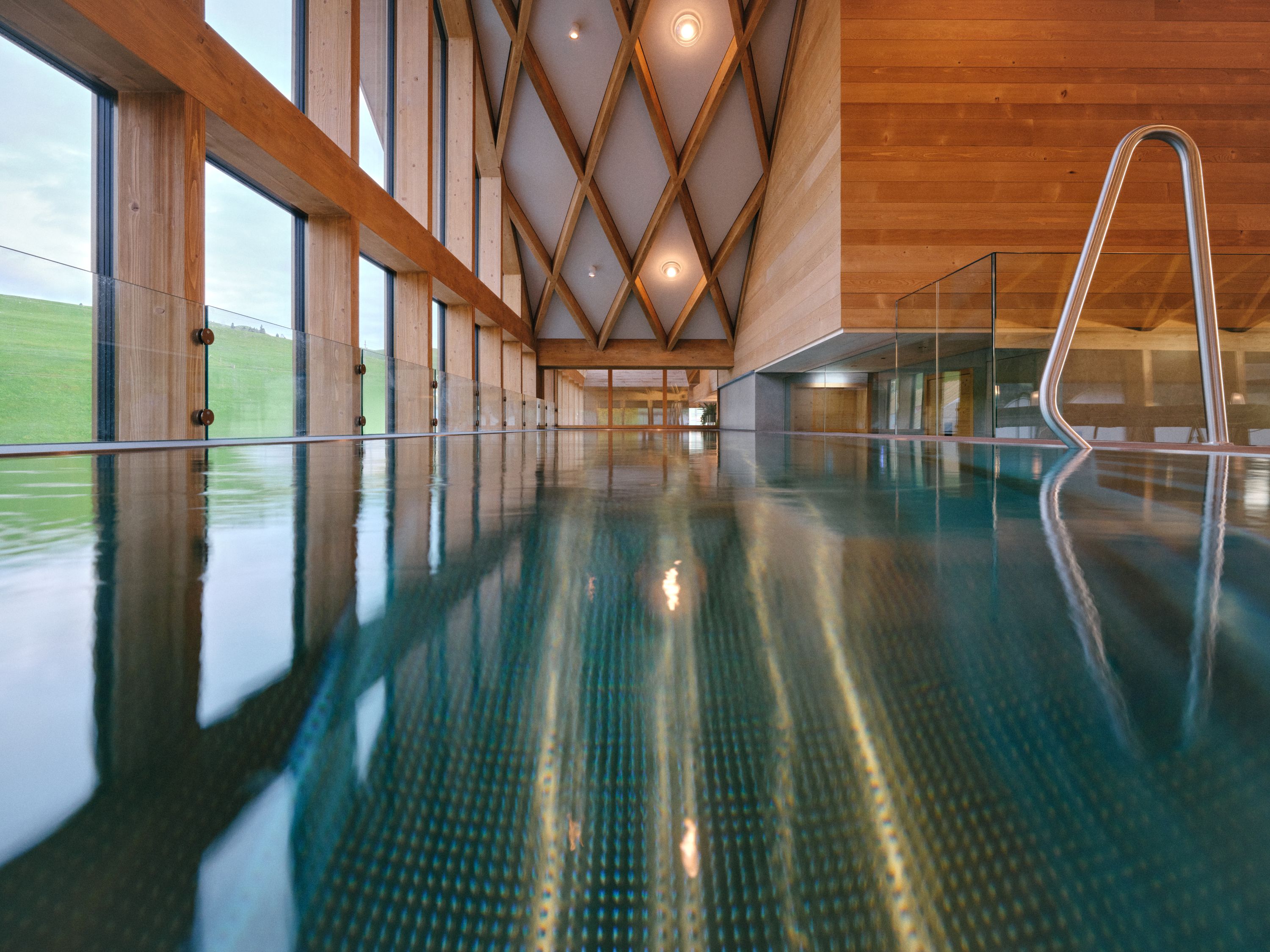 a indoor pool with glass walls and a roof