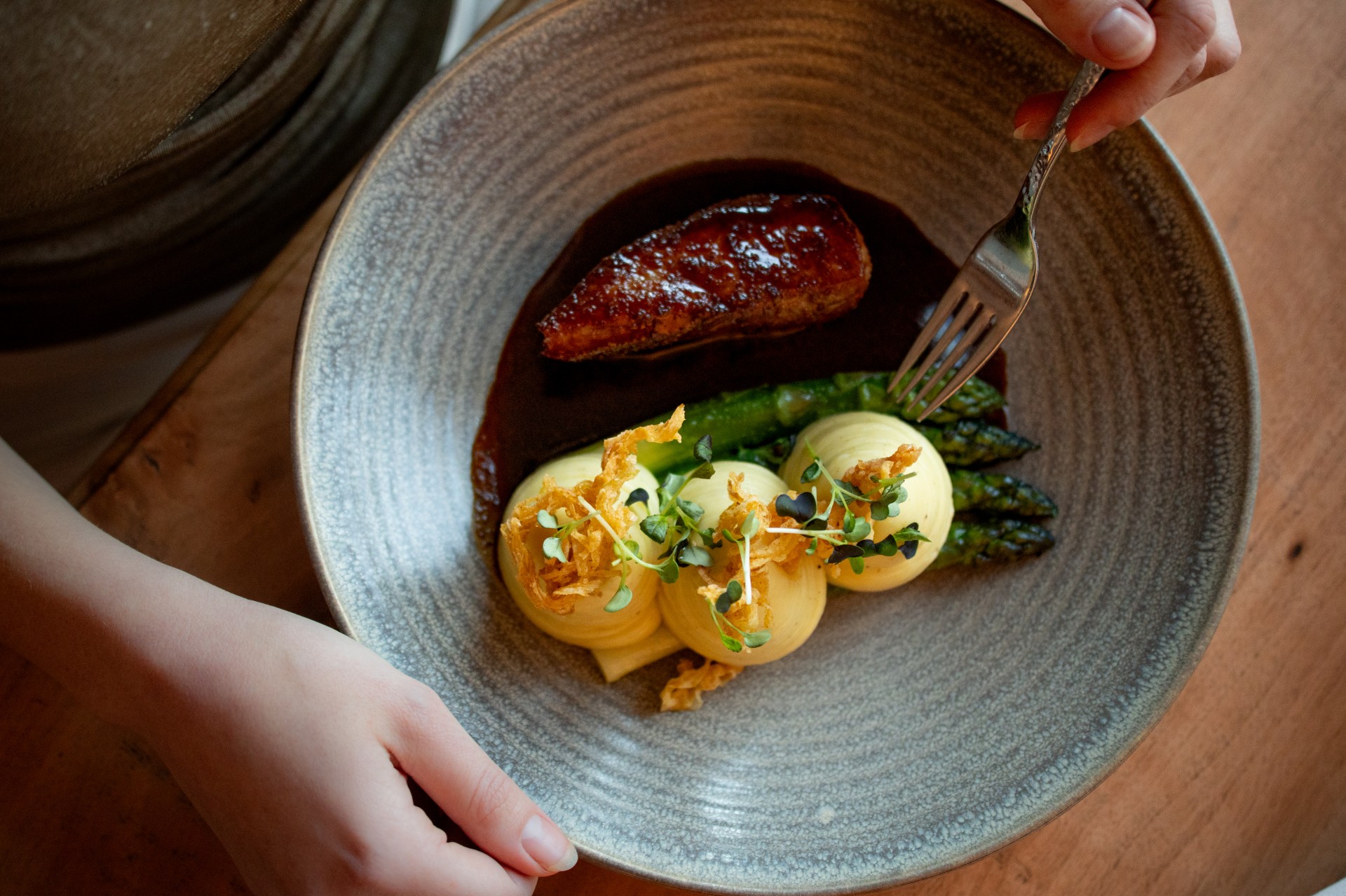 a person holding a fork over a plate of food