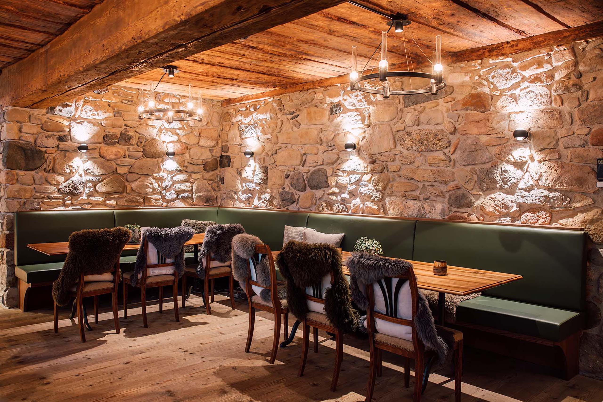 a room with a stone wall and a table with a bench and chairs