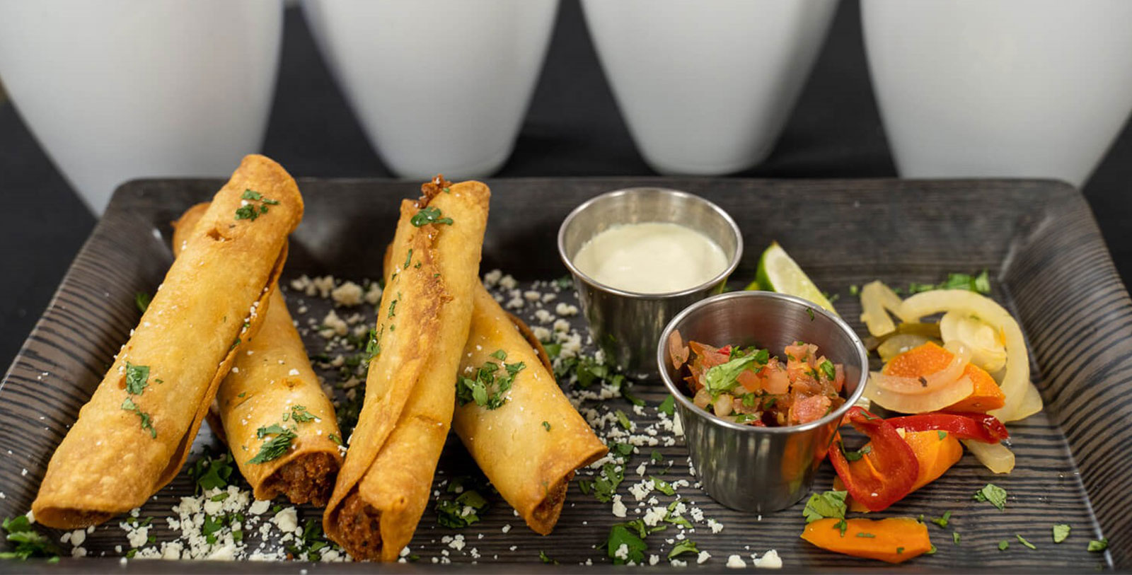 a plate of food with sauces and cups