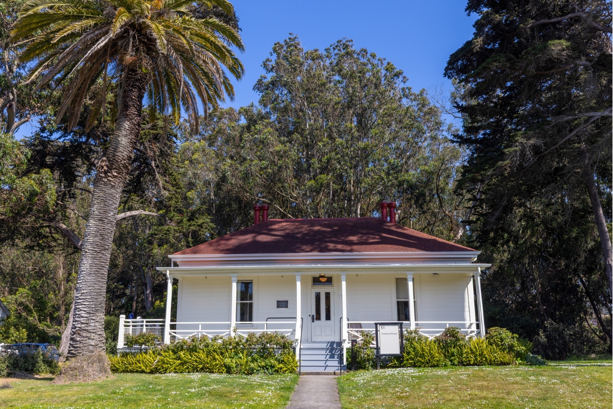 a white house with a red roof and a tree