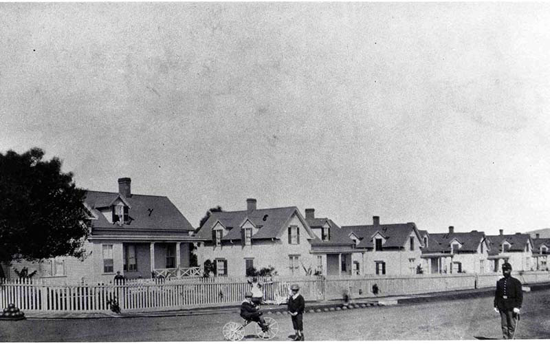 a couple of people walking in front of a row of houses