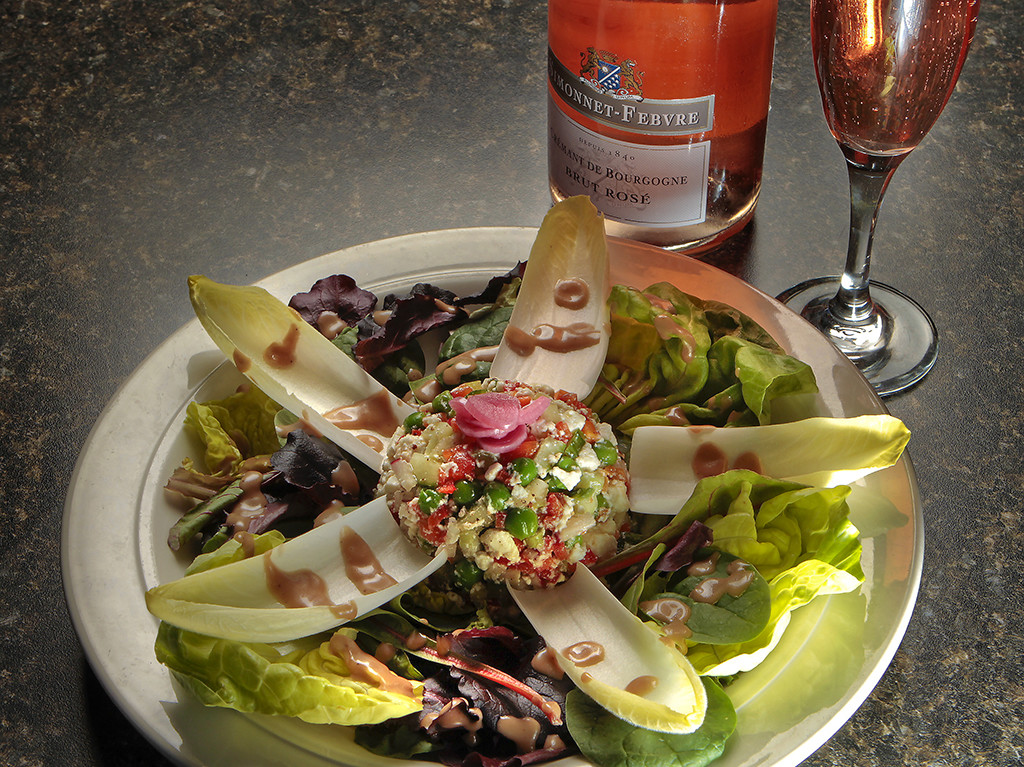 a plate of salad with a bottle of wine