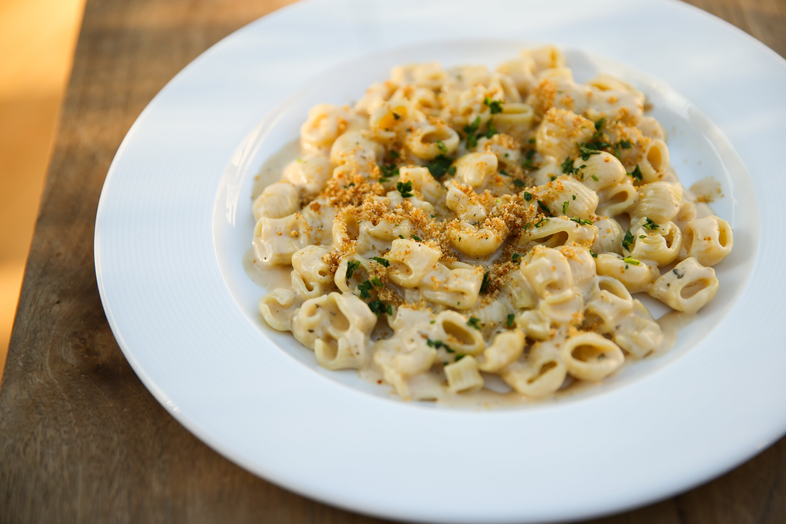 a plate of pasta with crumbs on top