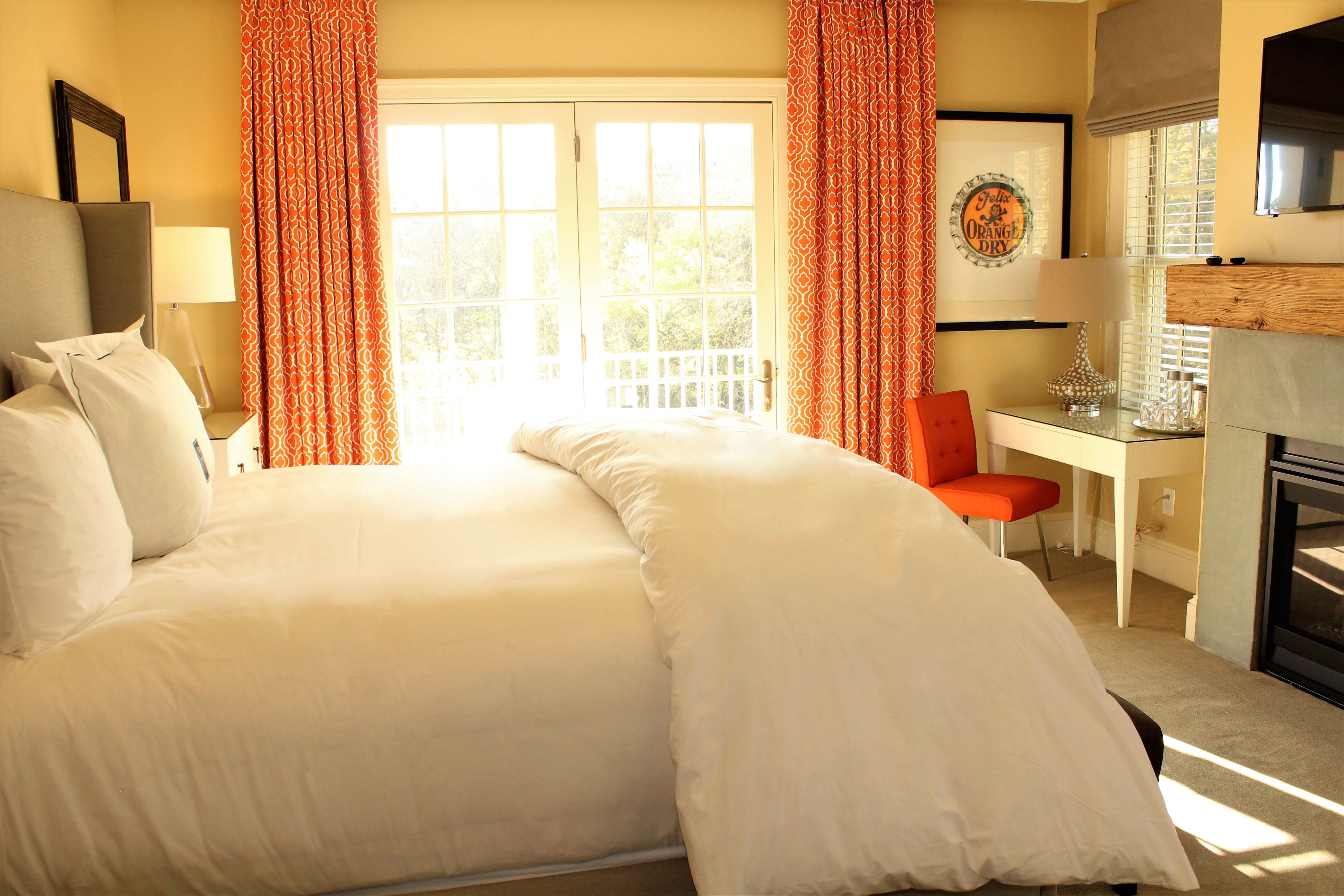 a bed with orange curtains and a desk
