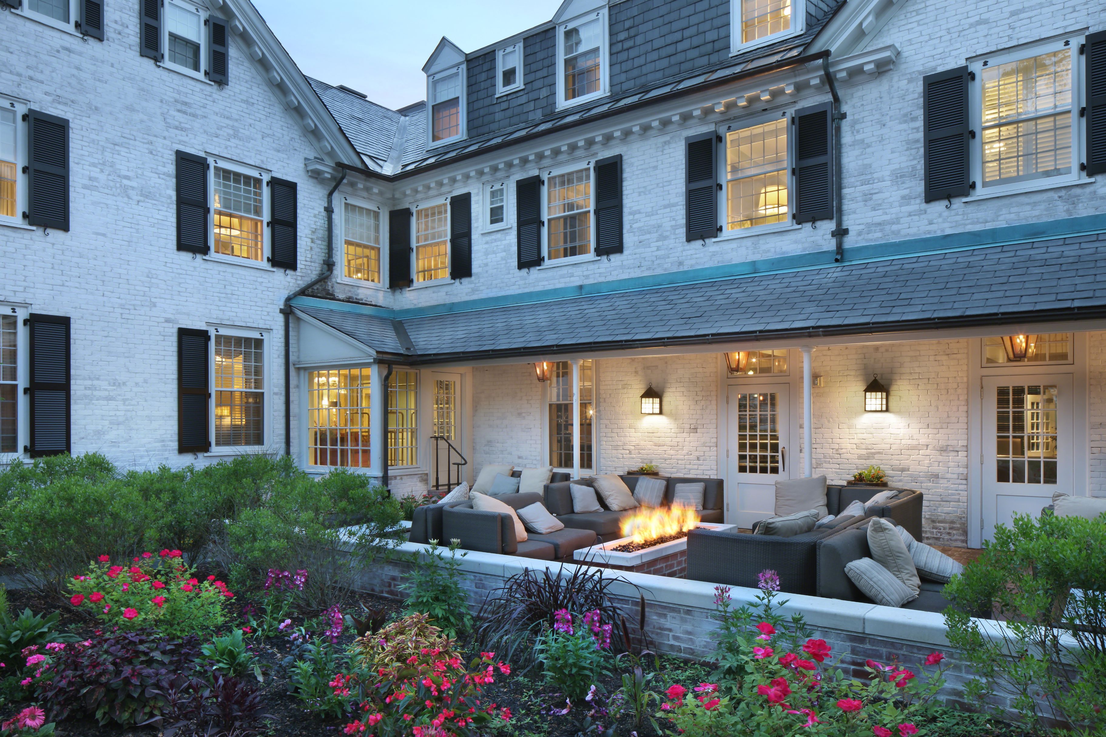 a large white house with a fire pit and flowers