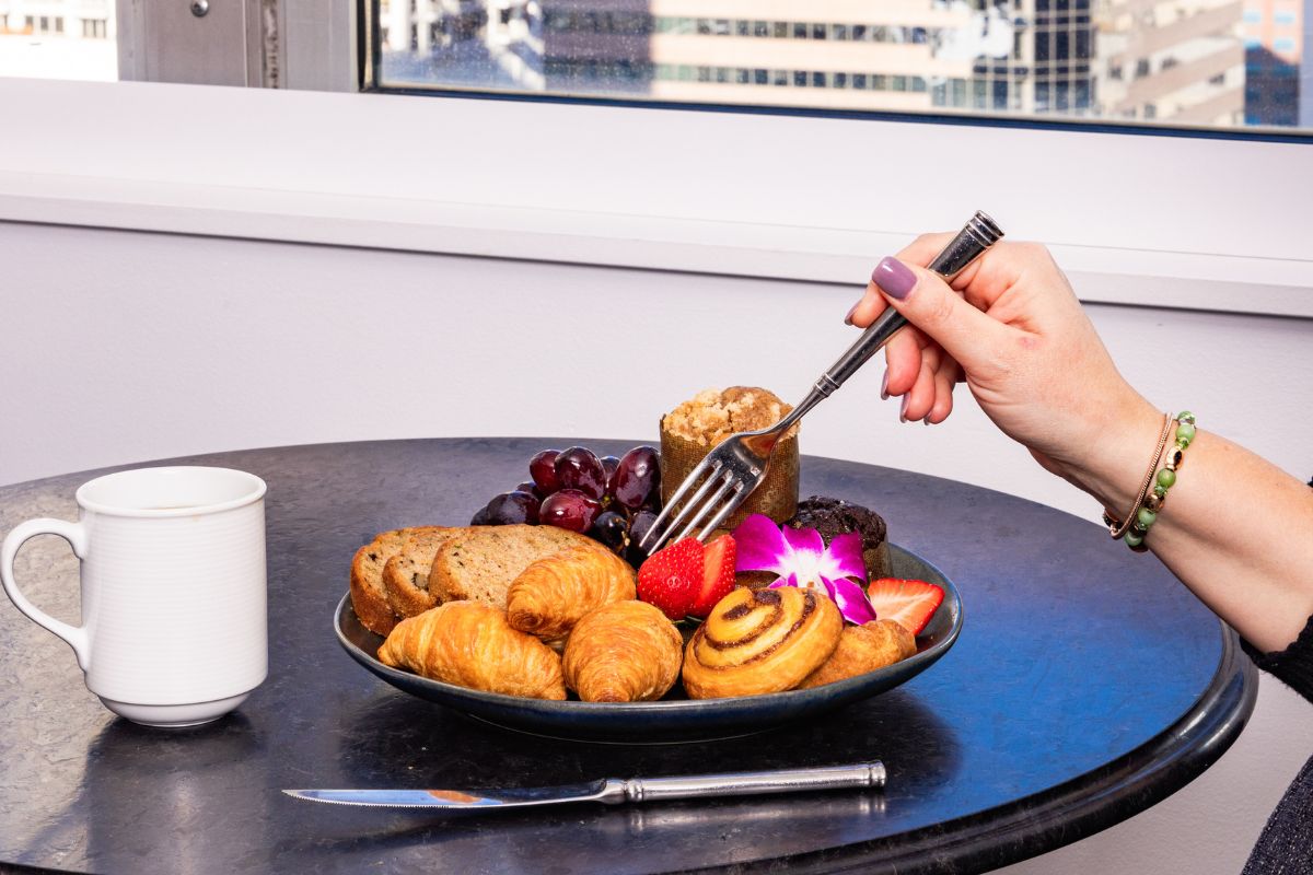 a hand holding a fork and a plate of food