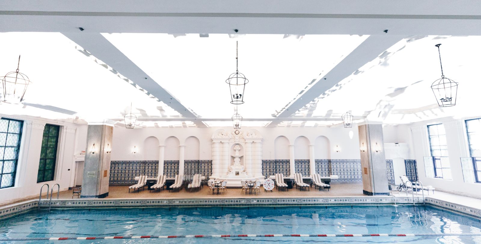 a swimming pool with chairs and a white wall