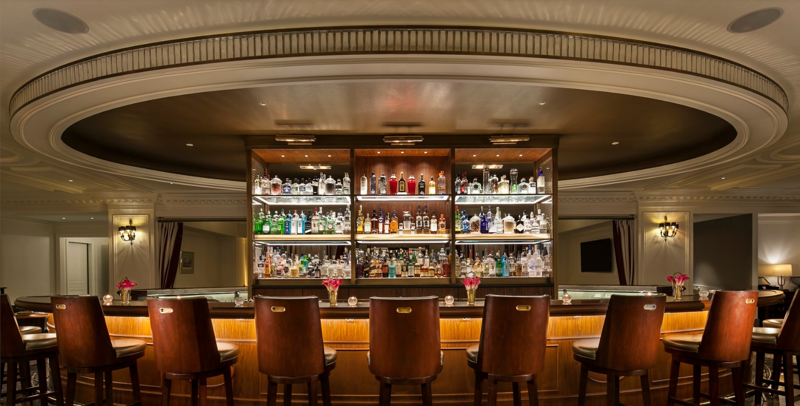 a bar with shelves filled with bottles and chairs