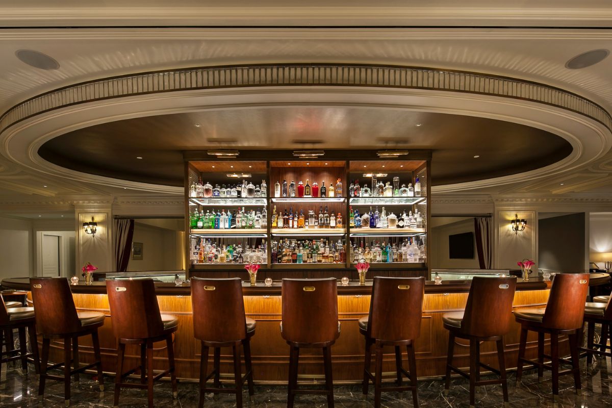 a bar with shelves of liquor and chairs