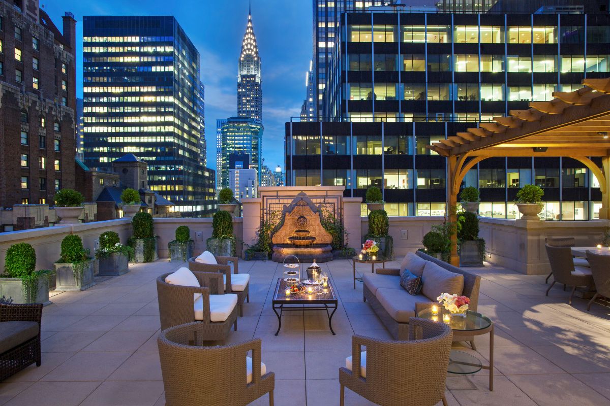 a rooftop patio with a table and chairs and a fountain in the background