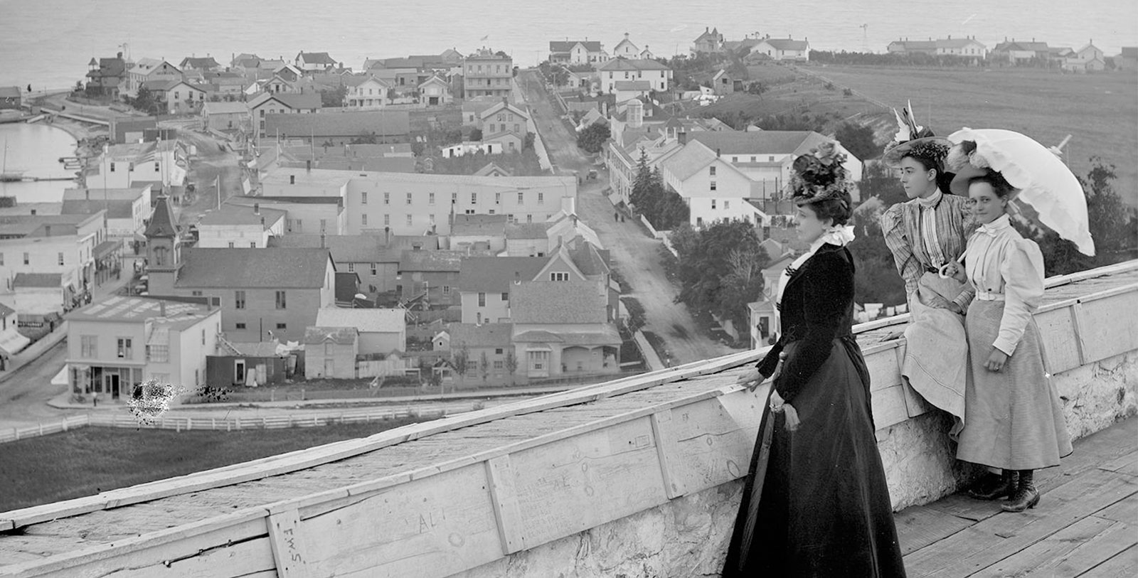 a woman in a dress standing on a ledge looking at a town