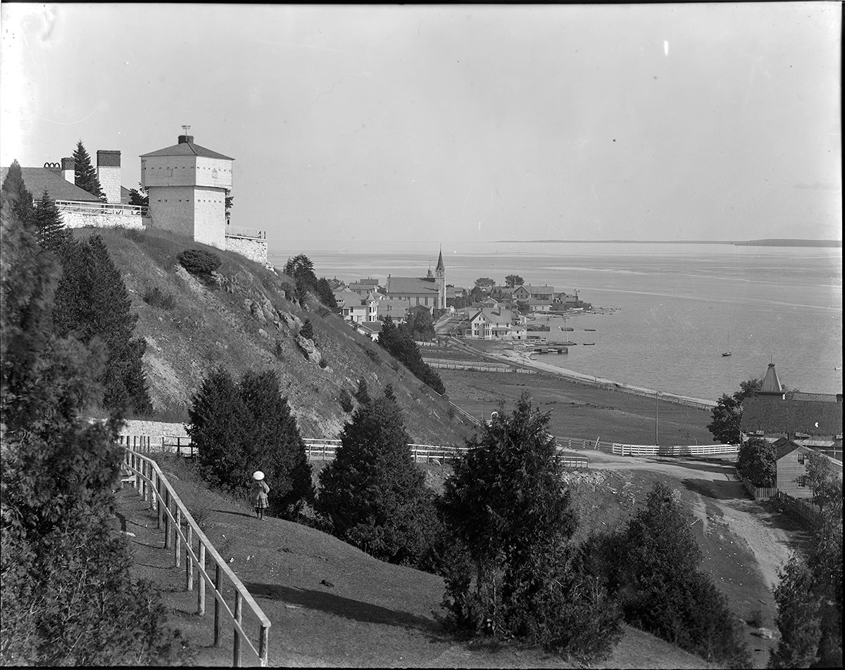 a black and white photo of a hill with a building and a body of water