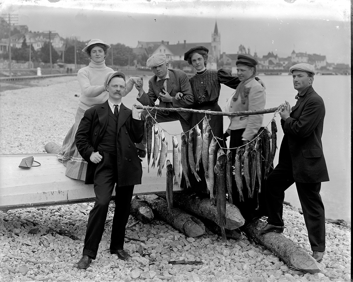 a group of people standing next to a row of fish