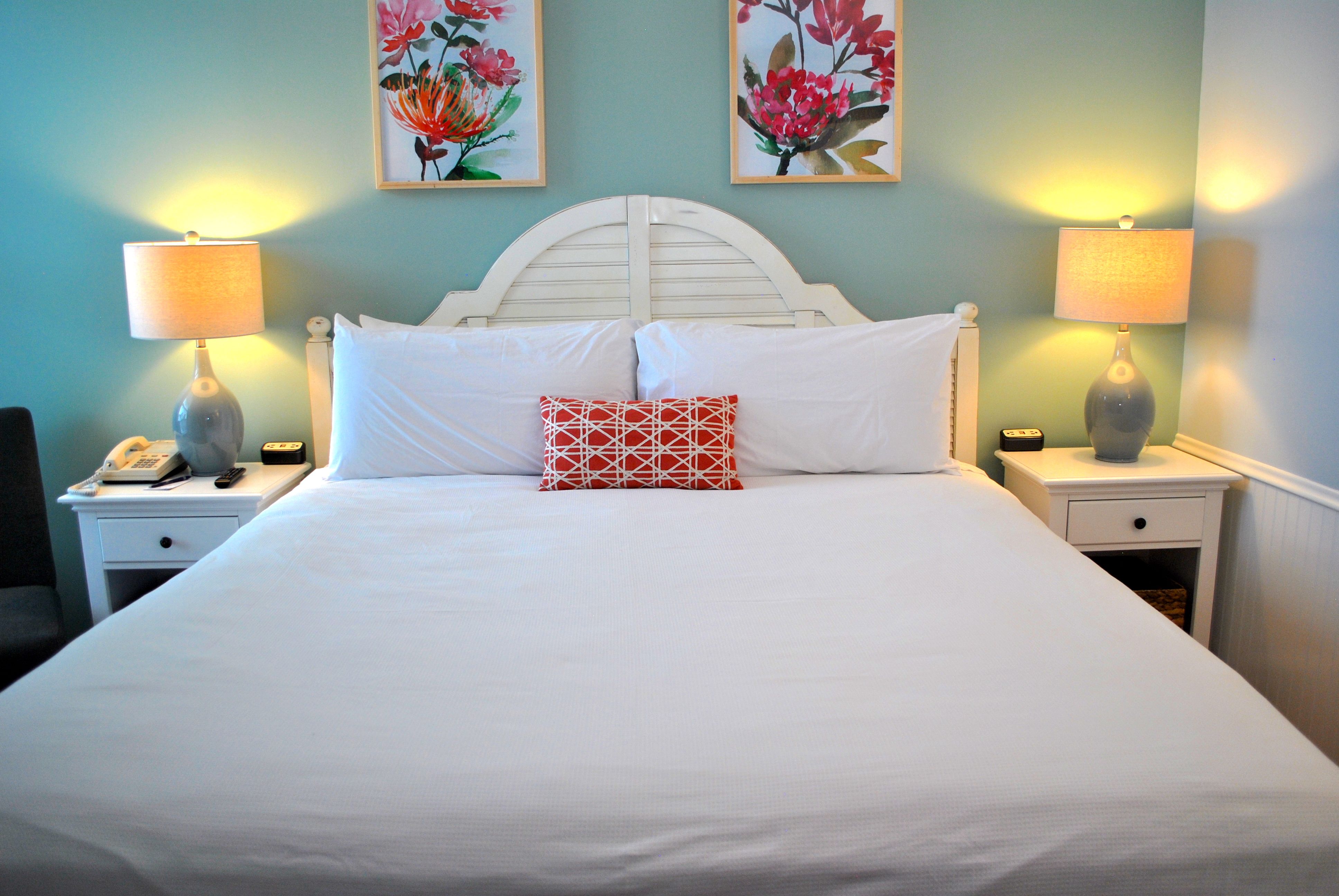 a bed with white sheets and red pillows