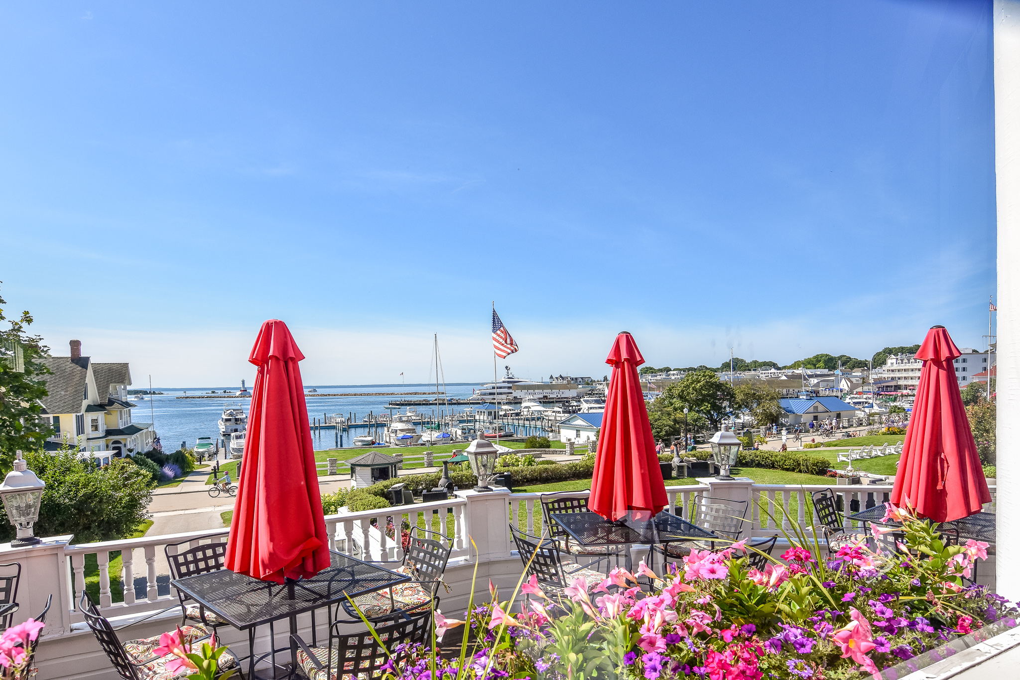 a patio with red umbrellas and flowers and a marina