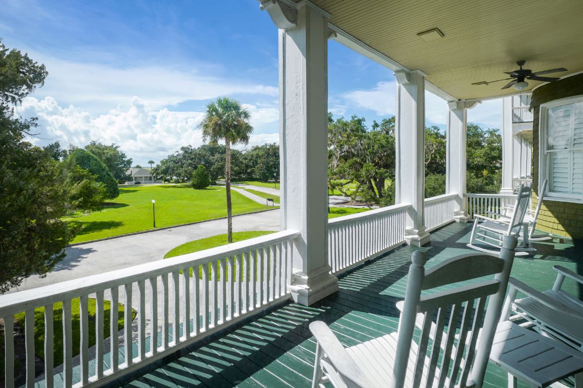 a porch with white pillars and a lawn and trees