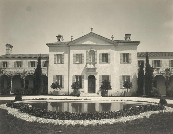 a large white house with a pond in front of it