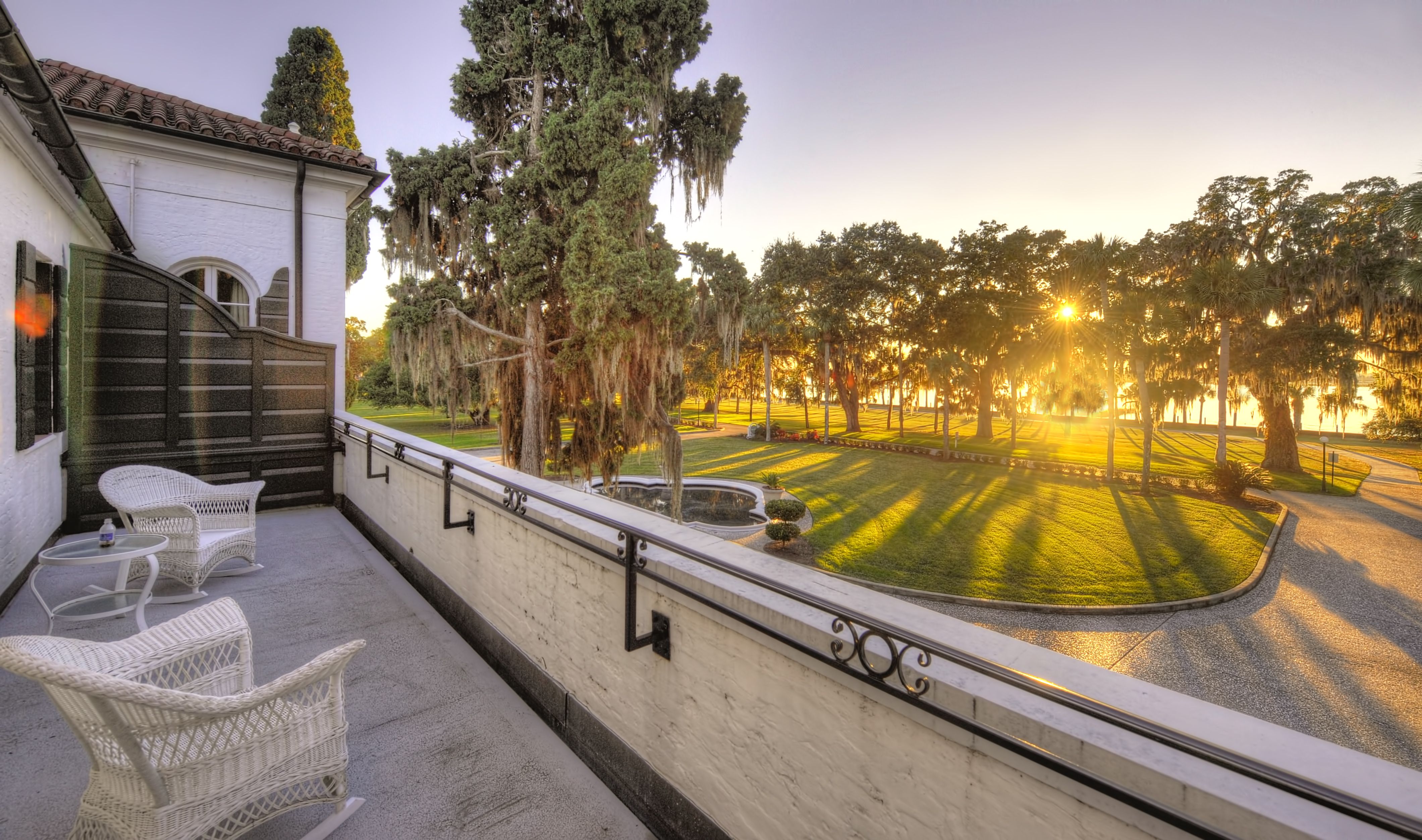 a balcony with a lawn and trees in the background