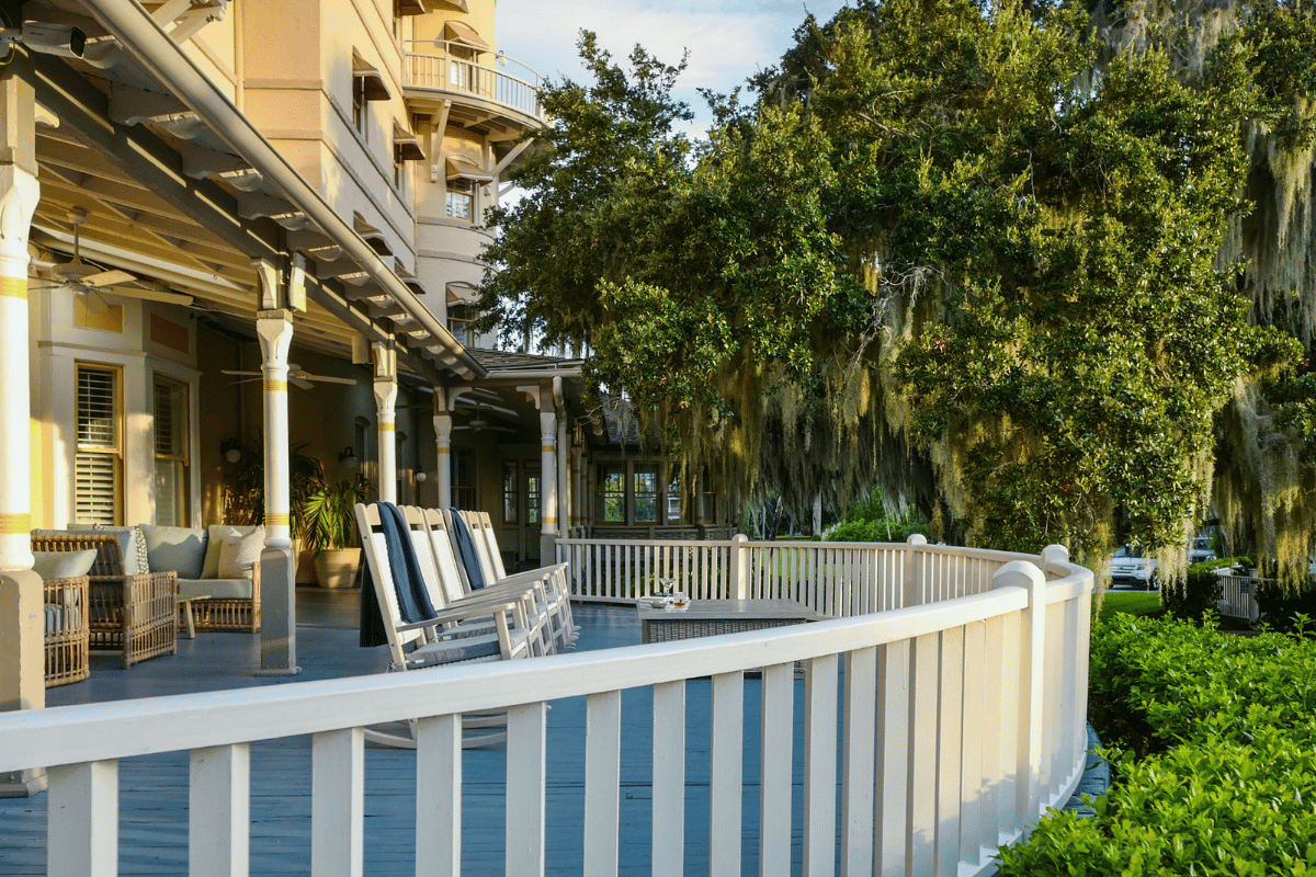 a white railing on a deck with chairs and trees in the background