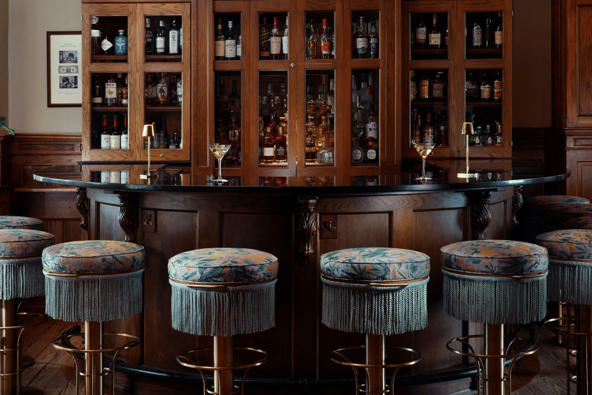 a bar with stools and drinks in the background