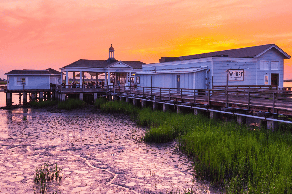 a building on a dock with a body of water and grass