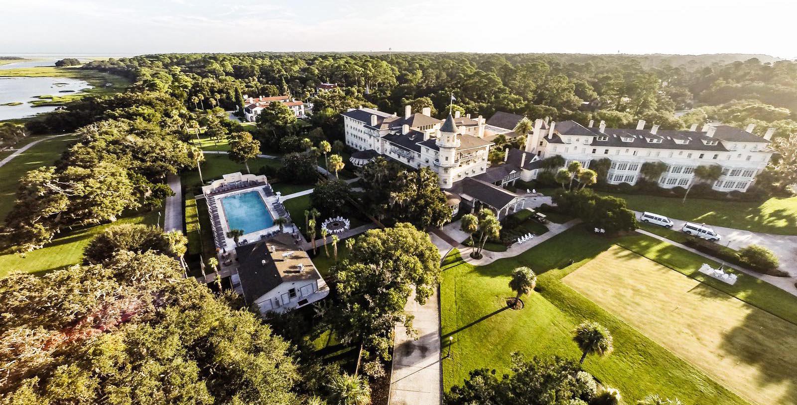 a large white building with a pool in the middle of a forest