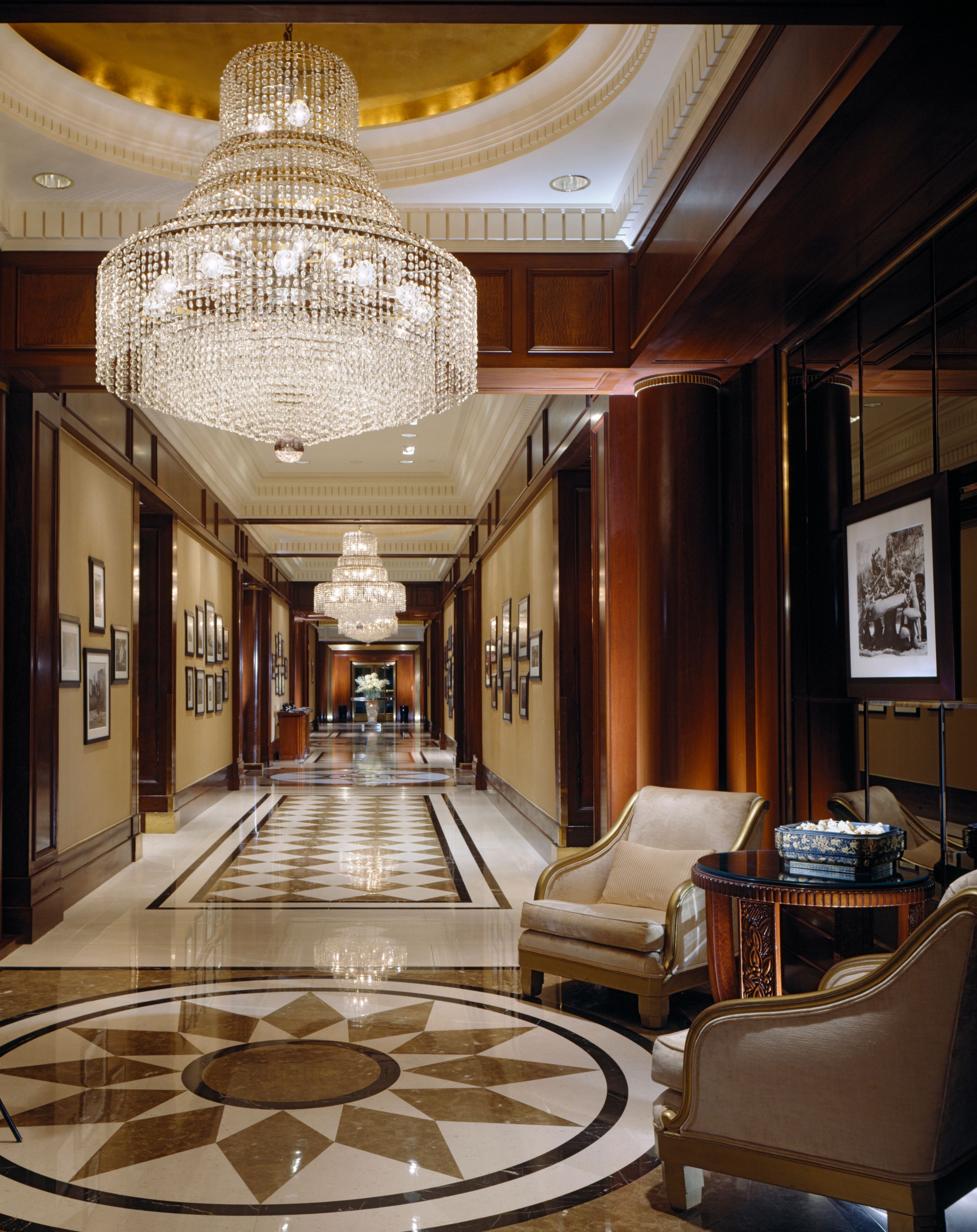 a long hallway with chandelier and chairs