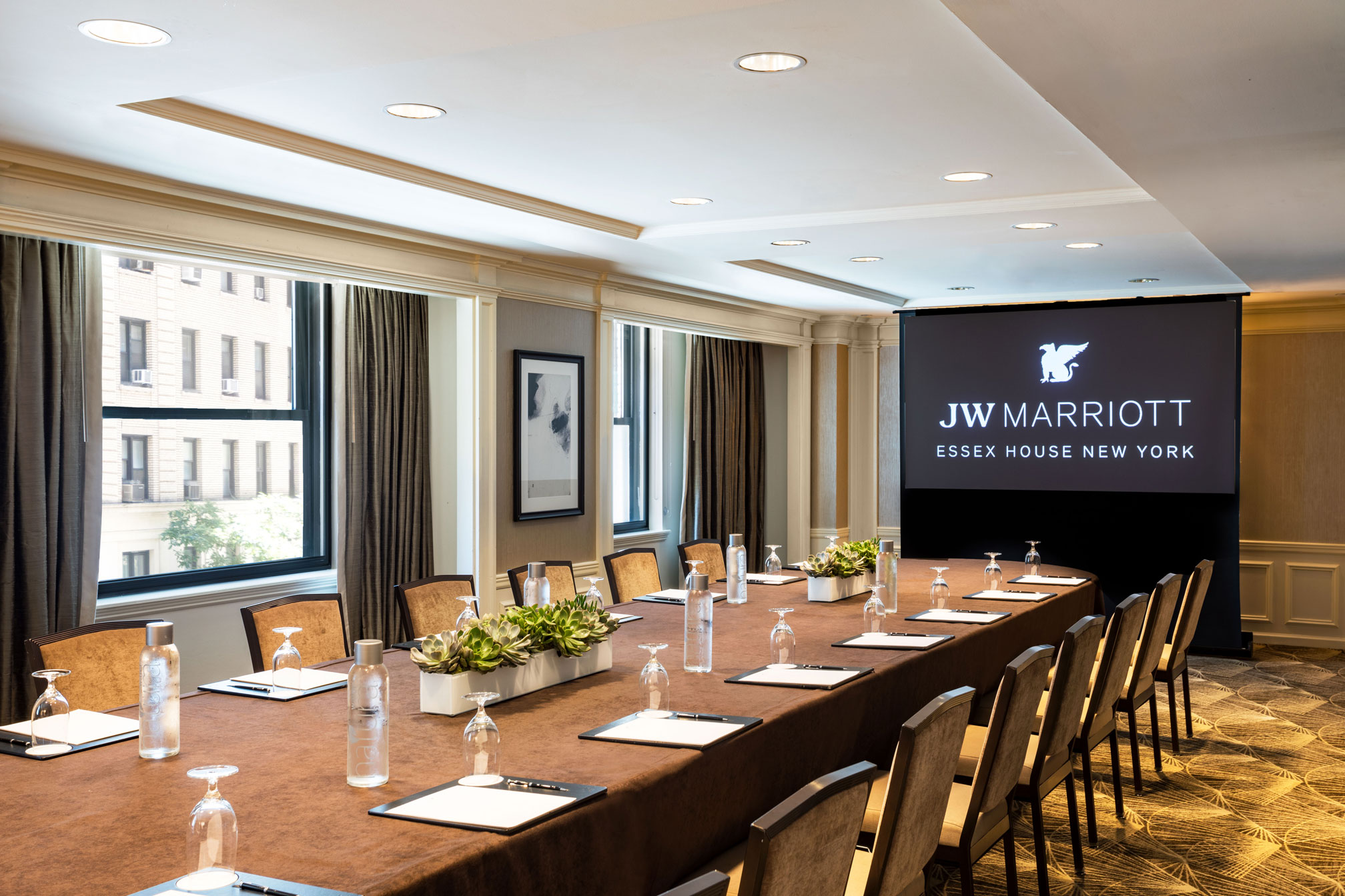 a long conference table with chairs and a projector screen