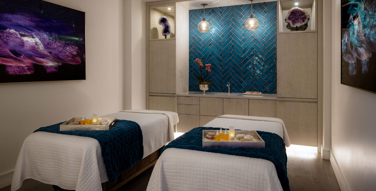 a room with two beds and a blue tile wall