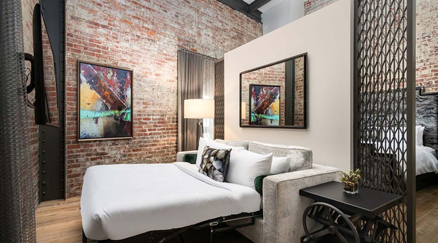 a bed in a room with a brick wall and a lamp