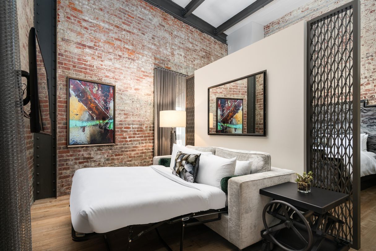 a bed in a room with a brick wall and a lamp